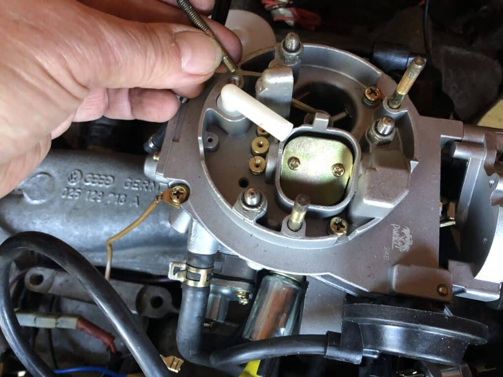 A hand refitting the ait intake stubs from the old Pierburg 2E3 carburettor onto the new Paruzzi 2E3 carburettor